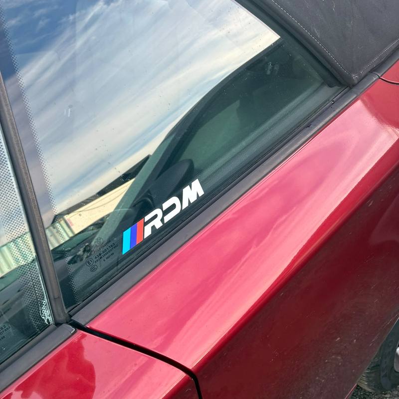 RDM window sticker on the rear side window of a red roadster