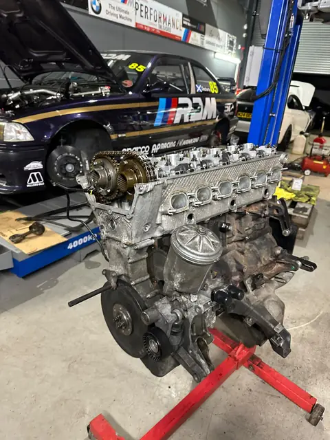 The rebuilt engine on its stand in front of car 85